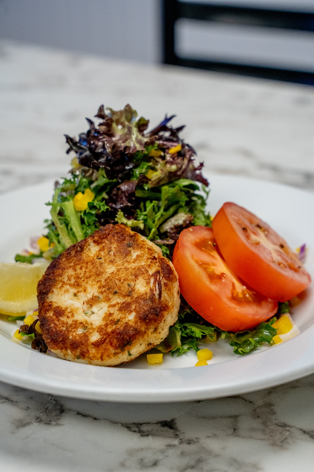 Crab cake with fresh mixed greens, tomato and lemon — Luc's Seafood & Grill