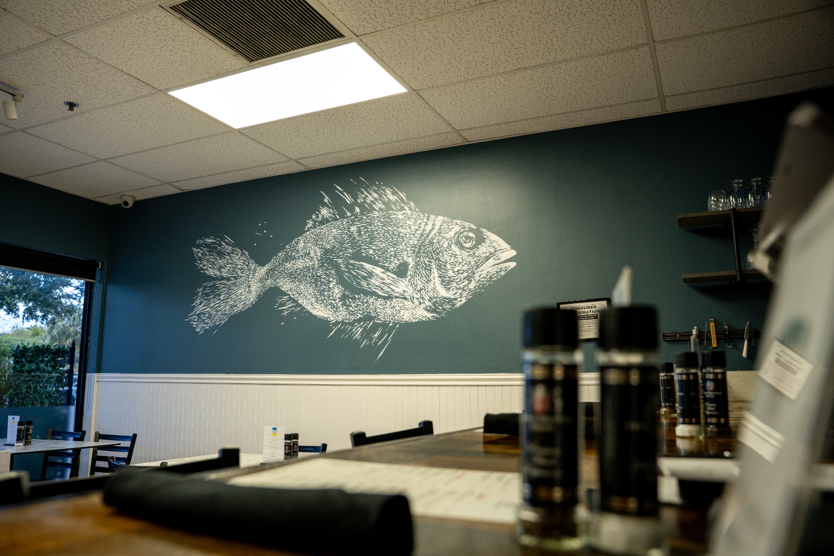 Full interior of Luc's Seafood & Grill featuring the iconic hand-painted fish mural on a navy wall