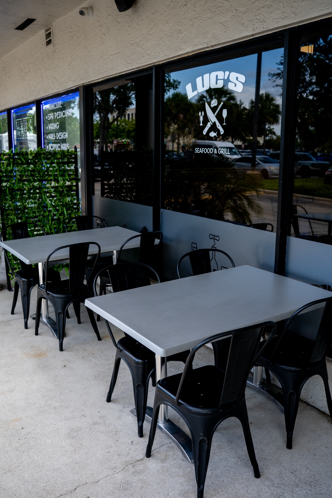 Outdoor sidewalk seating with black chairs and Luc's logo visible on the window